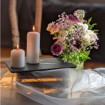 zwei brennende Kerzen und bunte Blumen