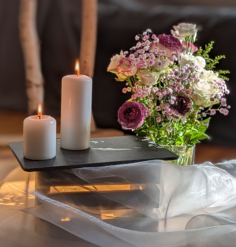 zwei brennende Kerzen und bunte Blumen